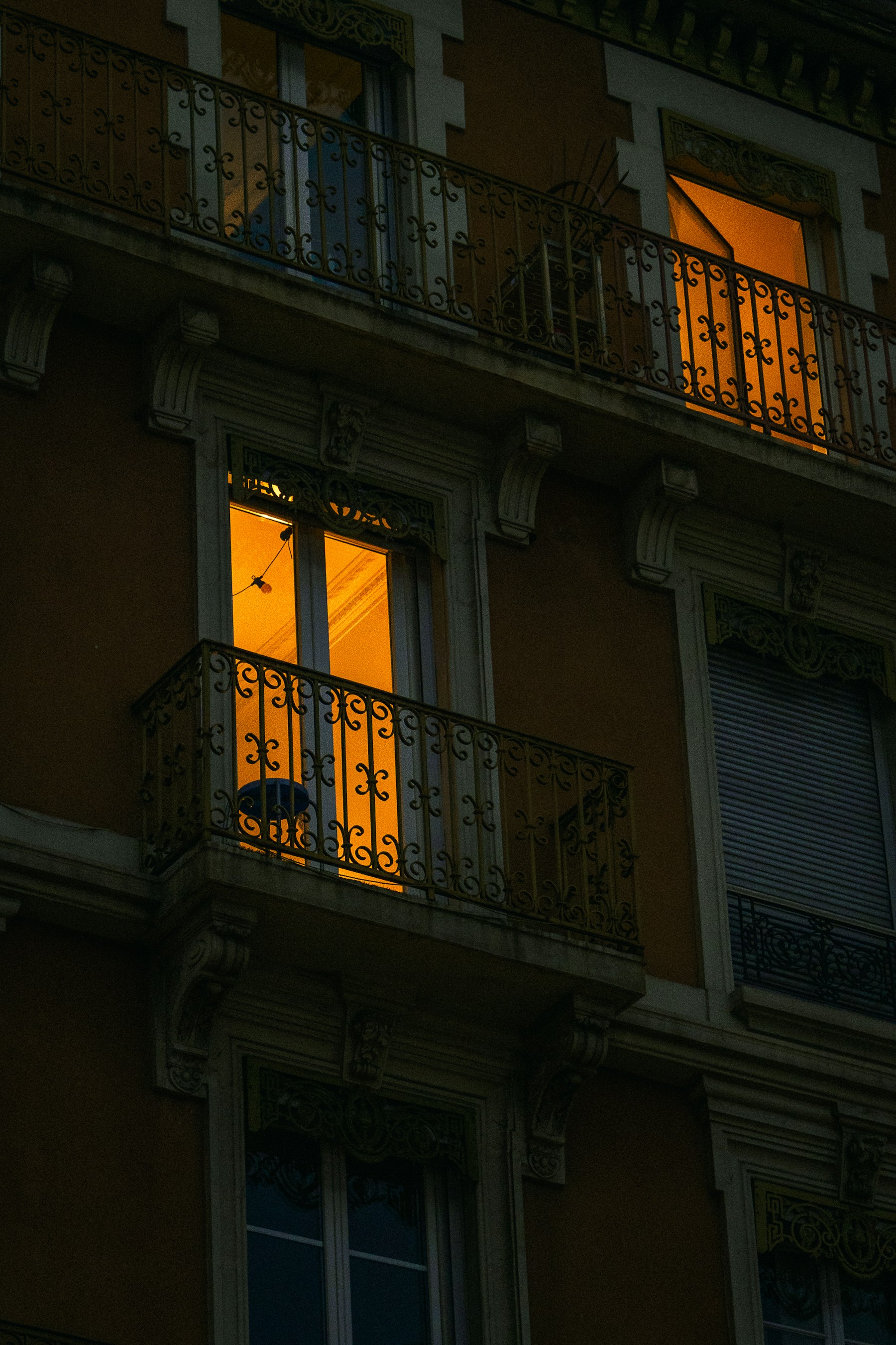 Traditional wrought-iron balcony grill on an older apartment facade — the cage look an invisible grill design replaces